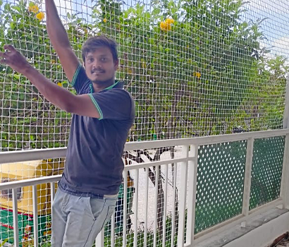 Balcony safety net installed in an apartment with a person hanging in the net to demonstrate its quality and durability
